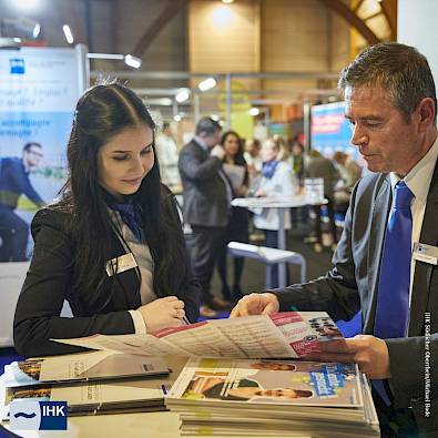 Messe Situation: zwei Menschen unterhalten sich über einen Flyer